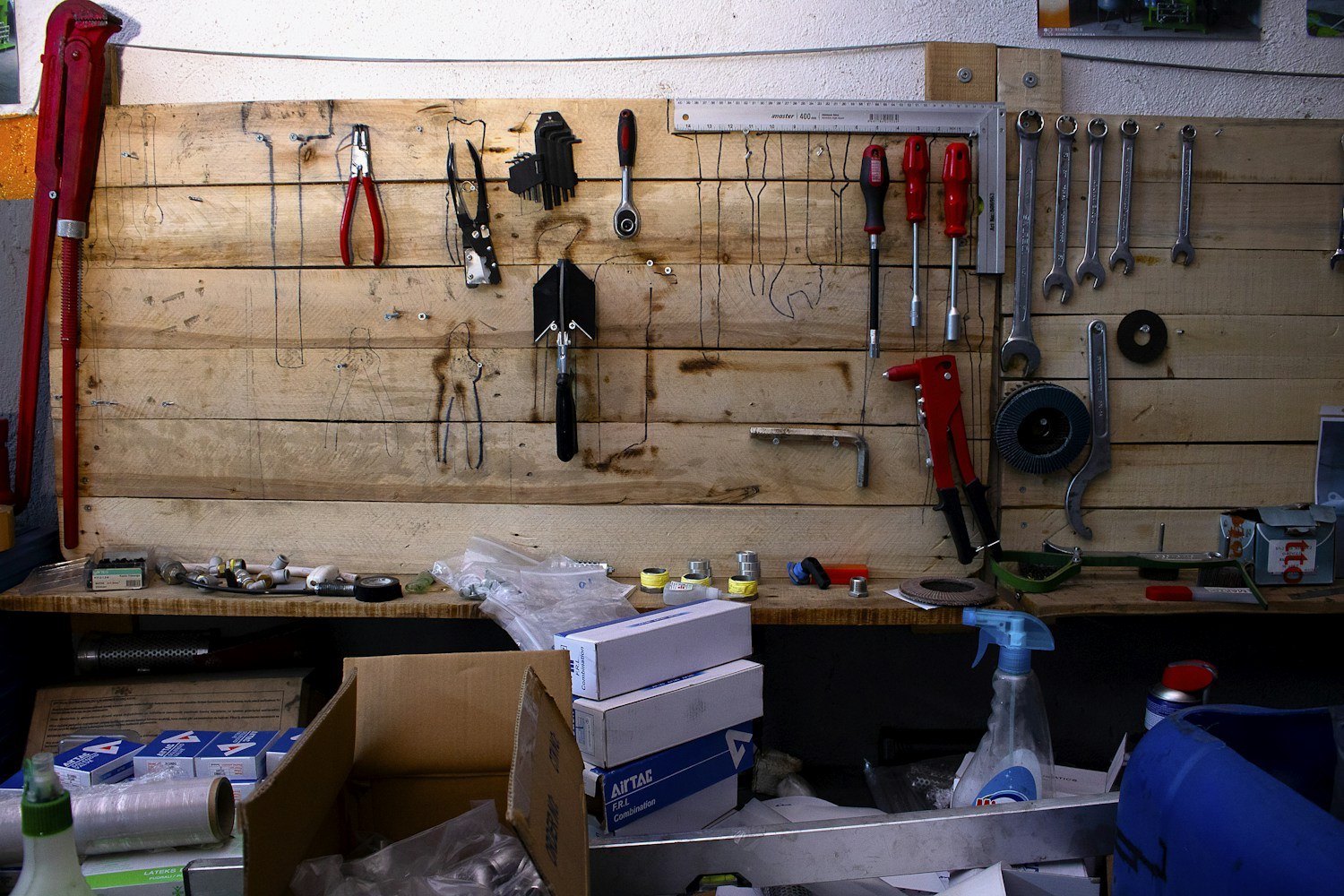 Tools hanging above a wooden workshop bench with supplies below